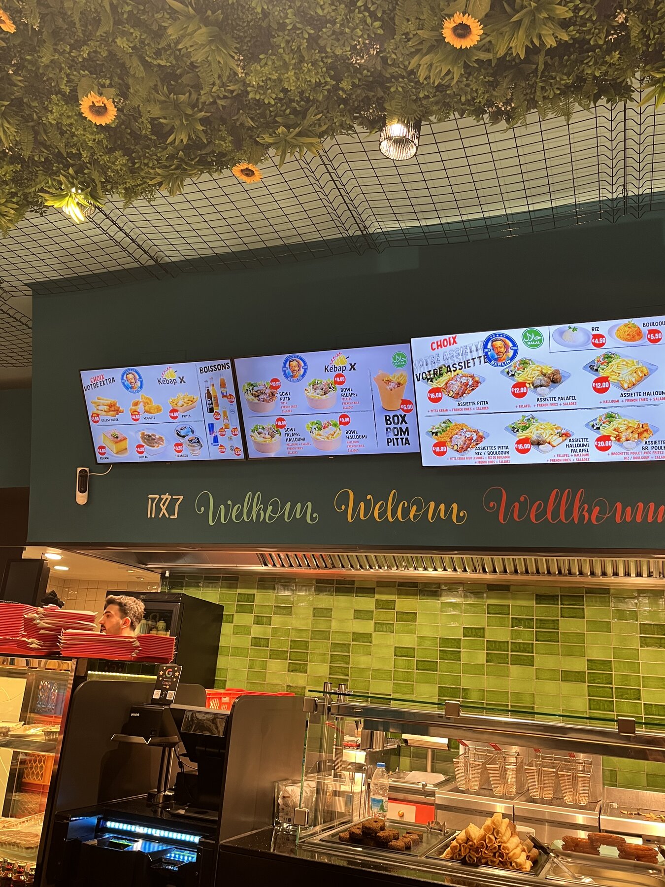 Welcome wall with menu screens above the counter